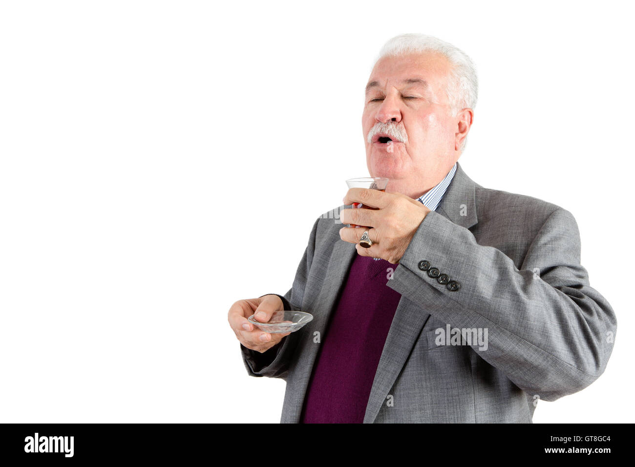 Senior distinguished white haired man enjoying a cup of Turkish tea savoring the flavor and aroma, isolated on white Stock Photo
