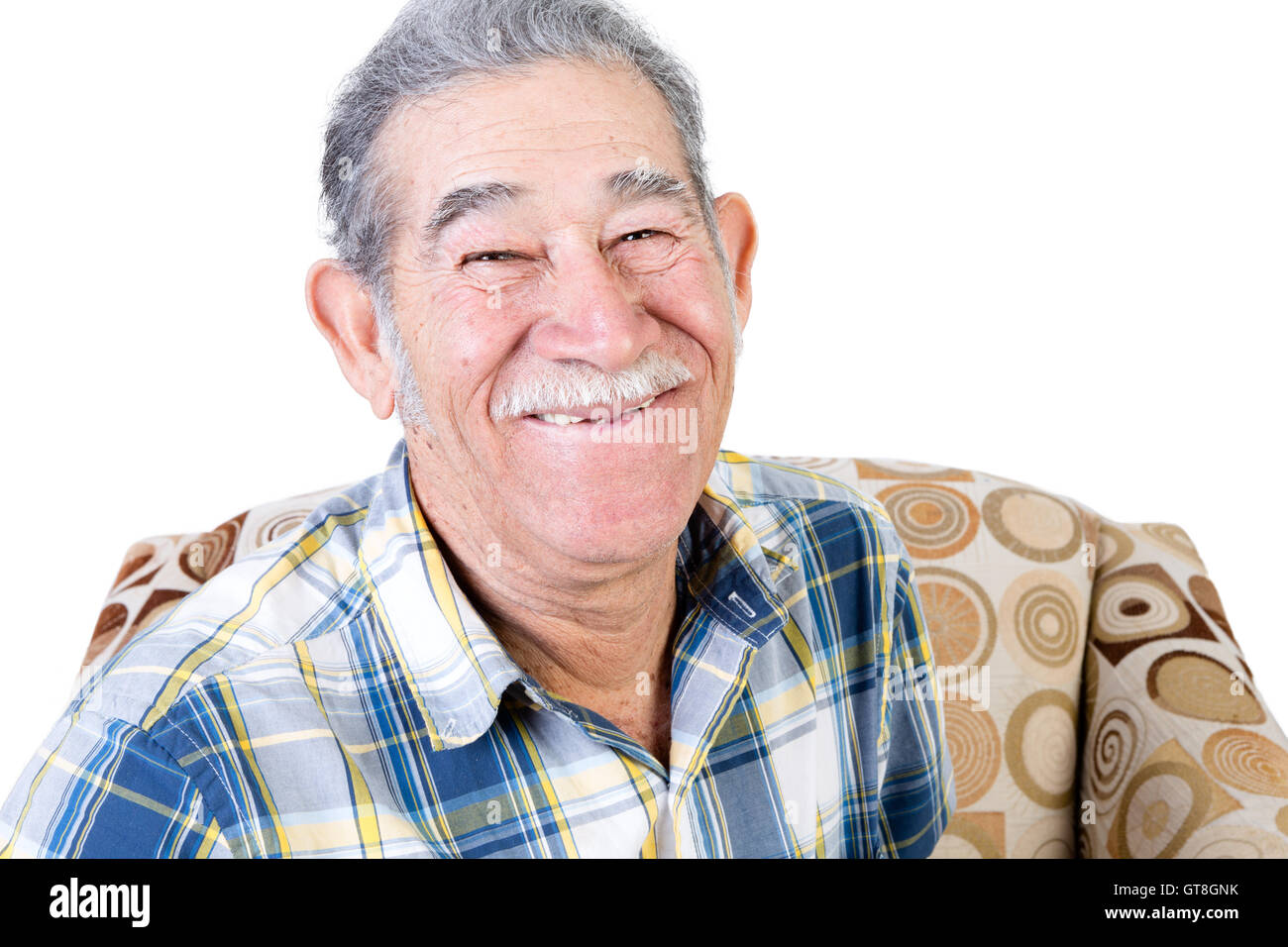 Handsome single Mexican man sitting on chair with big smile and mustache in flannel shirt Stock Photo