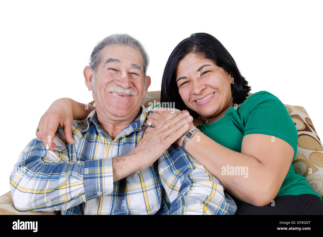 Happy Mexican senior with mustache touching hand of happy daughter sitting together on sofa Stock Photo