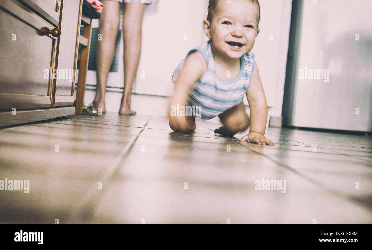 Happy baby boy crawling in the kitchen. Motion blurred Stock Photo