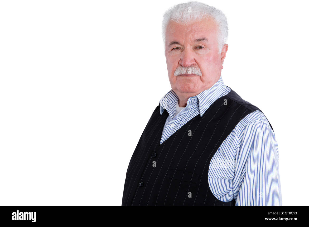 Firm and angry senior man wearing vest with intimidating and serious expression over isolated background Stock Photo