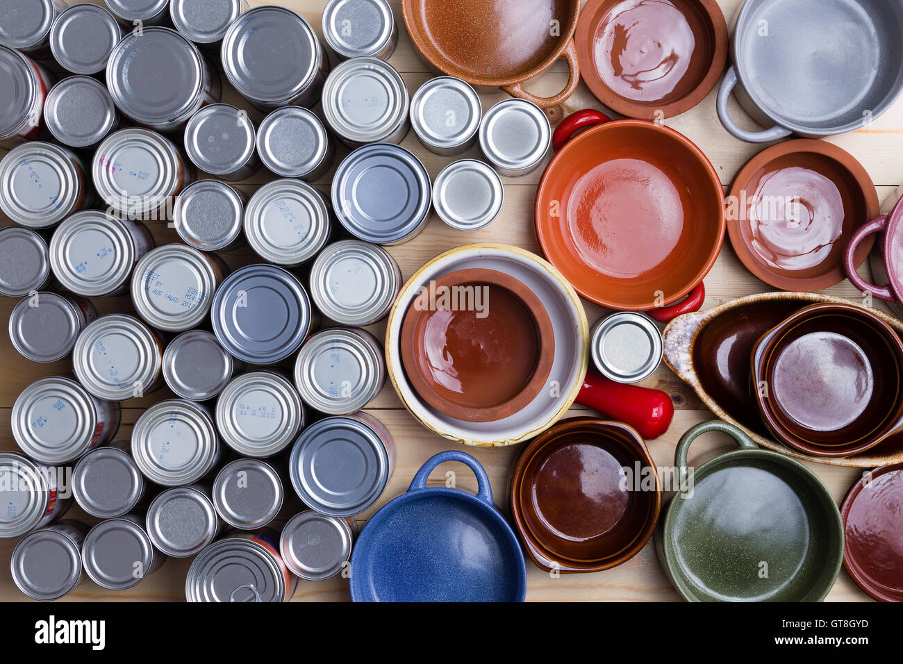 Top view of canned food containers next to multicolored empty bowls