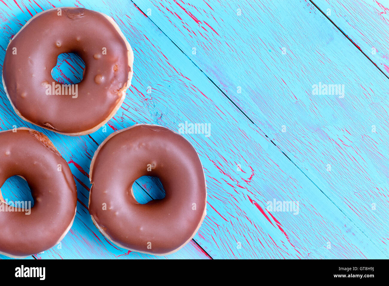 Three crispy cream filled chocolate ring donuts topped with chocolate