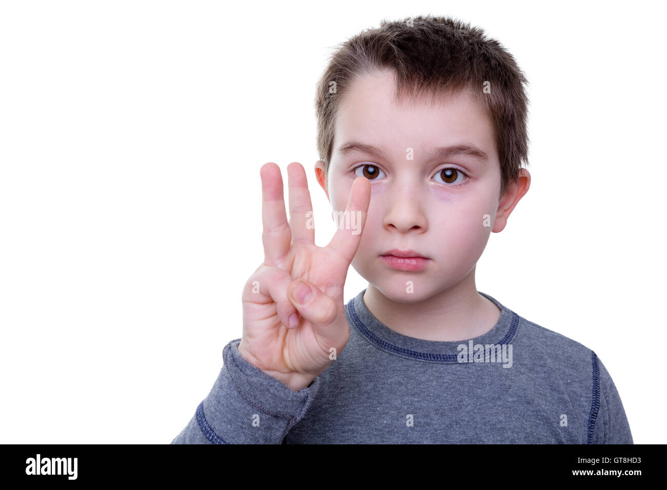 Close up of serious little boy gesturing with three fingers as if to count or display a symbol Stock Photo