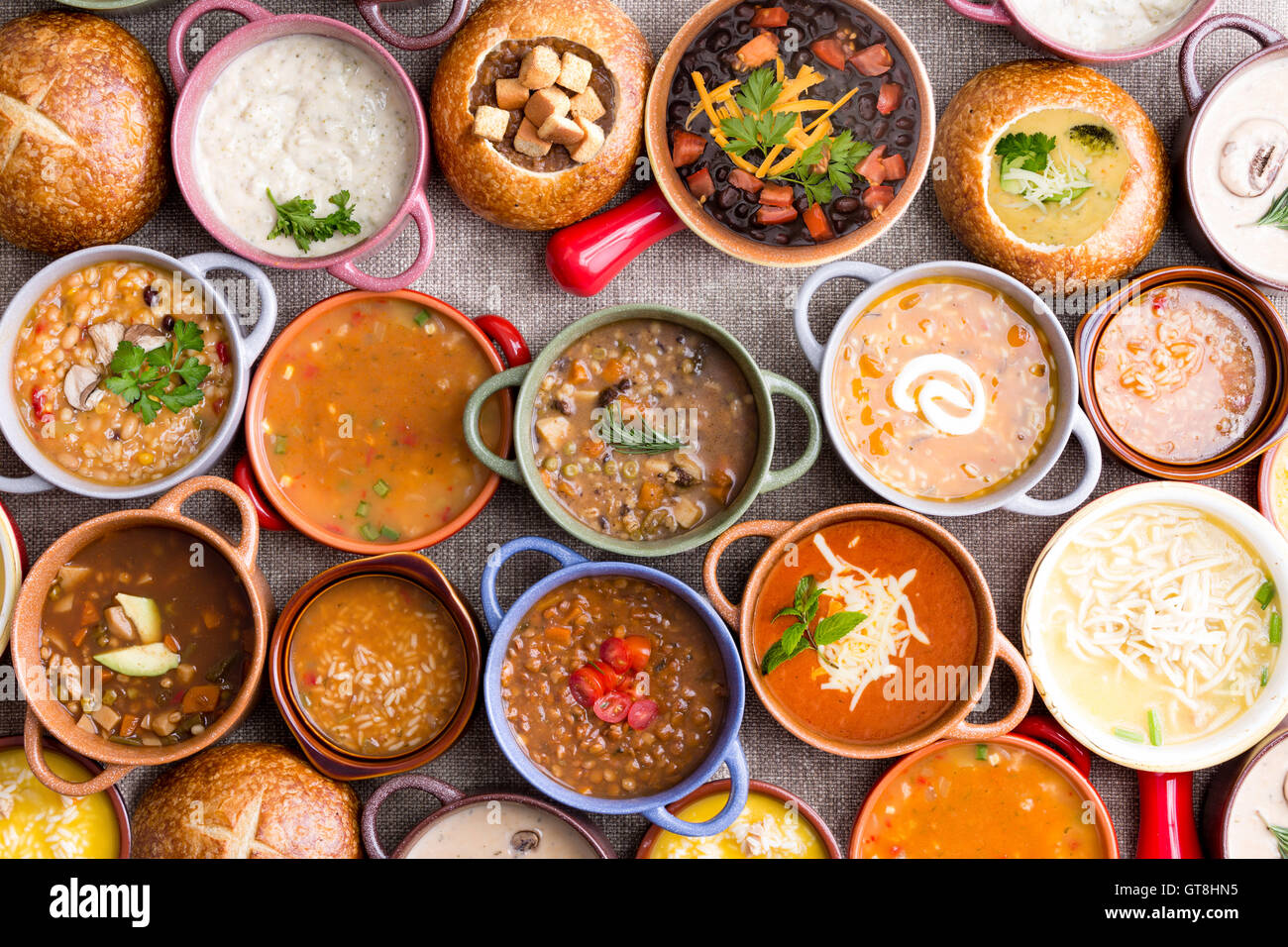High Angle View of Various Comforting and Savory Gourmet Soups Served in Bread Bowls and Handled Dishes and Topped with Variety Stock Photo