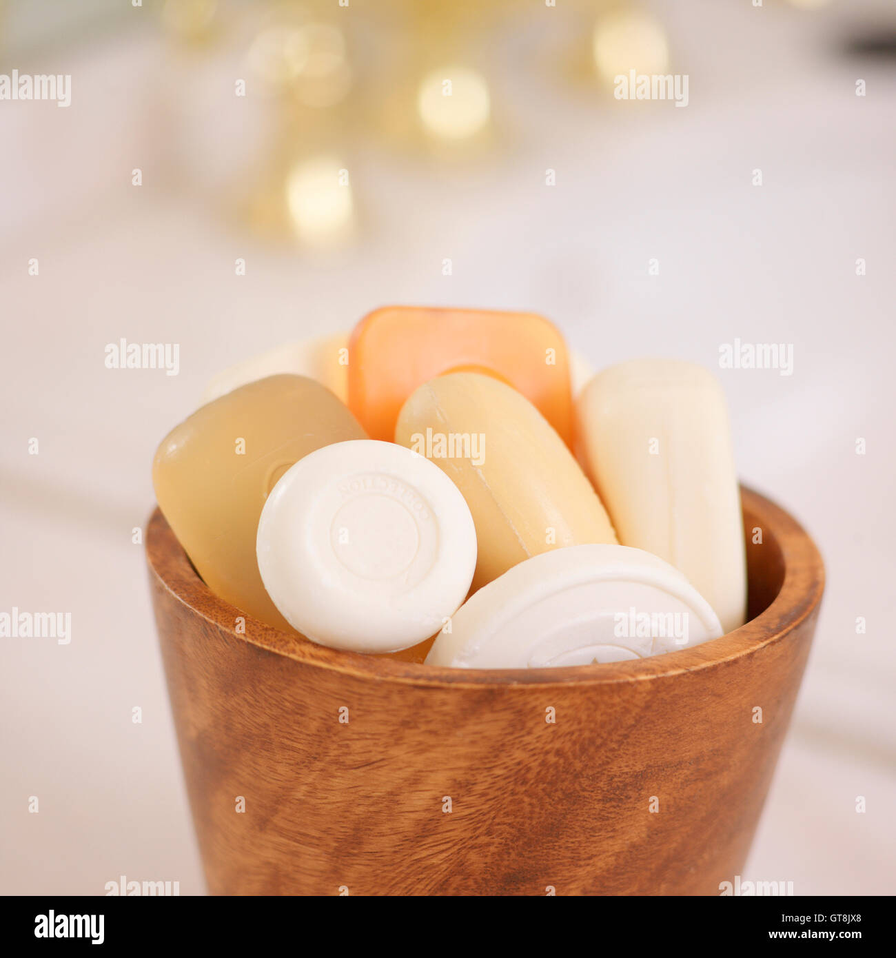 Variety of Bars of Soap in Wooden Bowl with Gold Sink Faucet in the Background Stock Photo