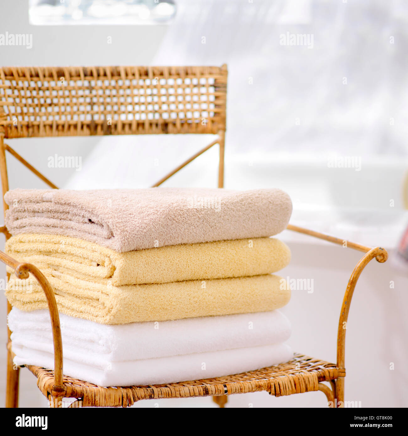 Stack of Fresh Towels on Wicker Chair in Bathroom Stock Photo
