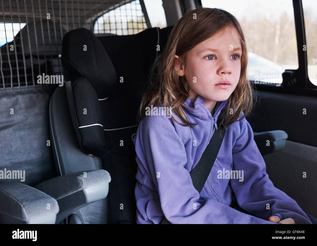 6 year old girl sitting in a car staring dreamily, Germany Stock Photo