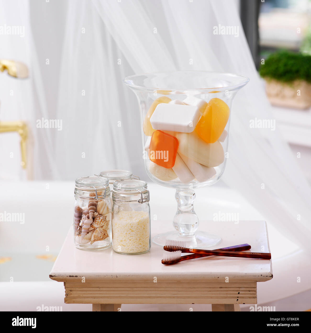 Side Table in Bathroom with Jars of Soap, Seashells, Bath Salts and Toothbrushes Stock Photo