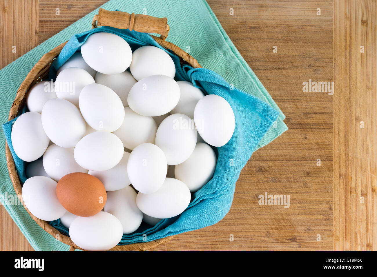 Wicker basket full of white eggs with one brown egg on the top in a conceptual image of diversity and individualism, overhead vi Stock Photo