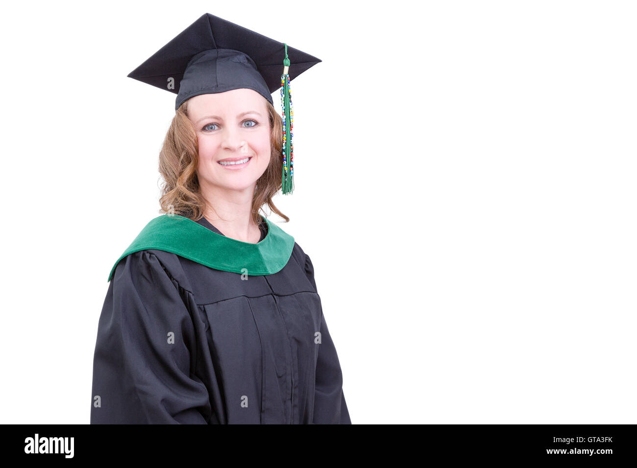 Pretty middle-aged academic in graduation clothing wearing a mortarboard cap and gown looking at the camera with a pleased happy Stock Photo