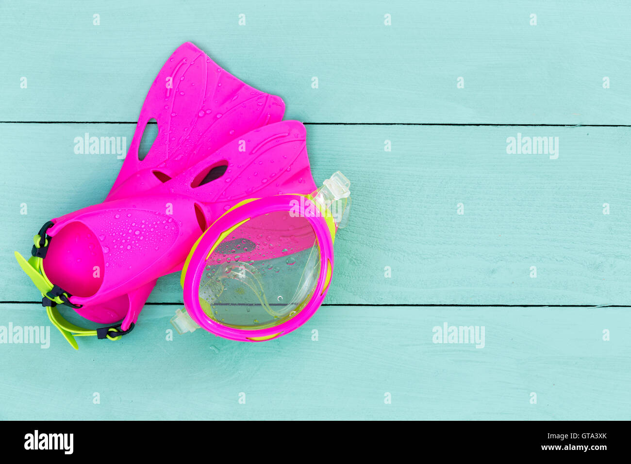 Colorful vibrant pink kids goggles and flippers arranged diagonally in