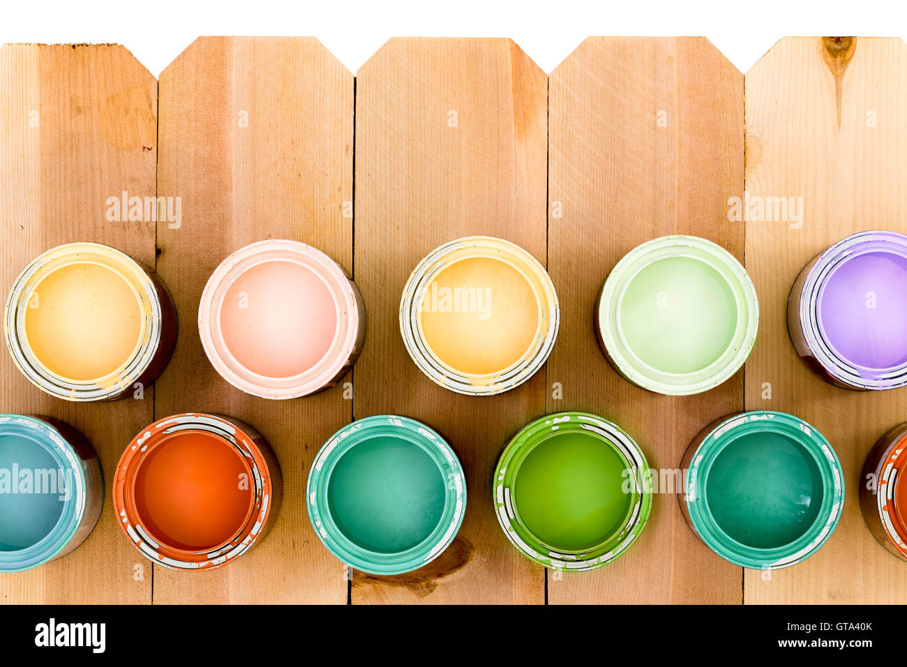Opened pots of colorful wood stain arranged as a lower border on a natural wooden picket fence offering a choice of colors to su Stock Photo