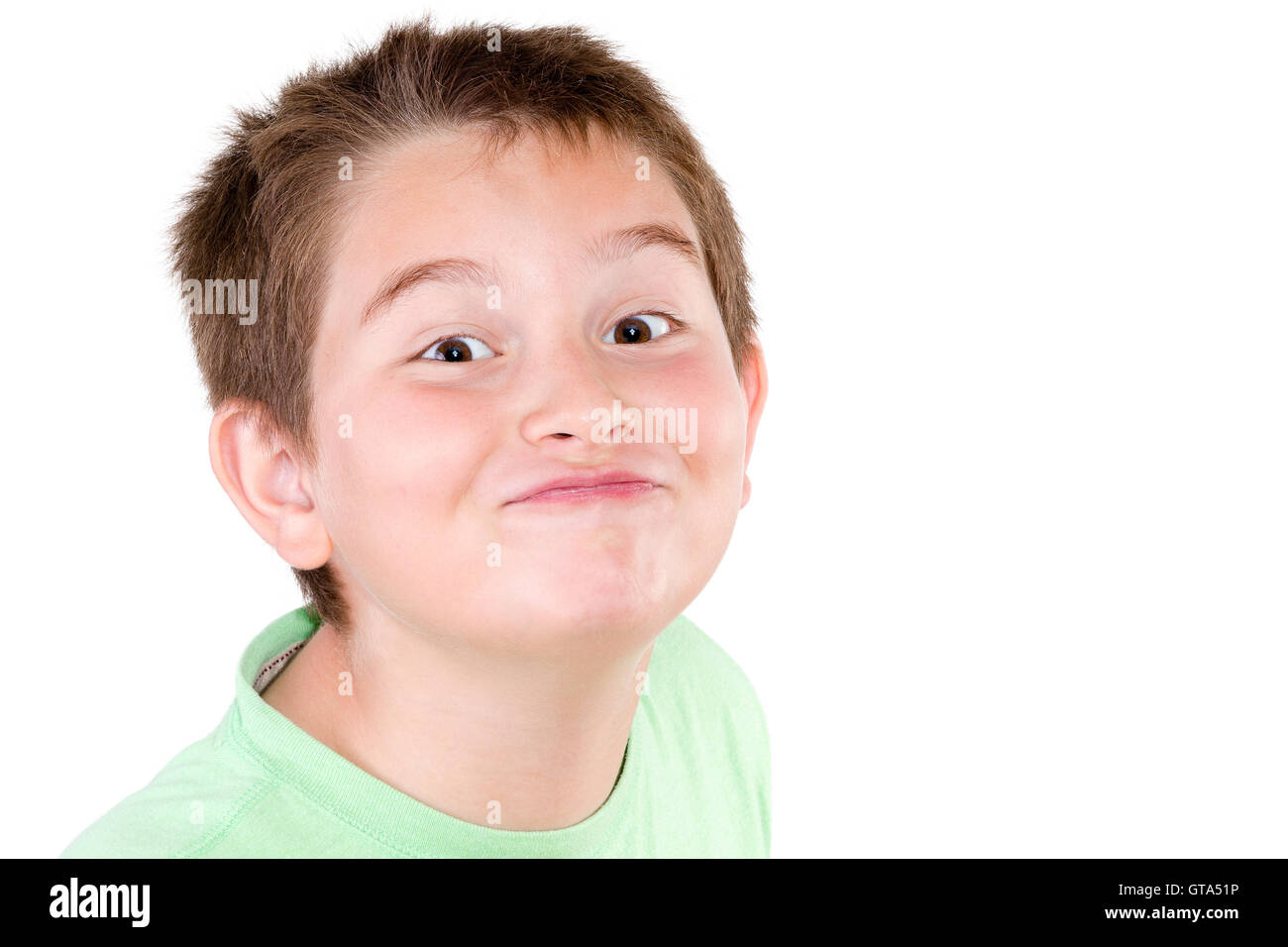 Playful mischievous young boy pulling a cute funny face at the camera with a jaunty look, head shot isolated on white Stock Photo