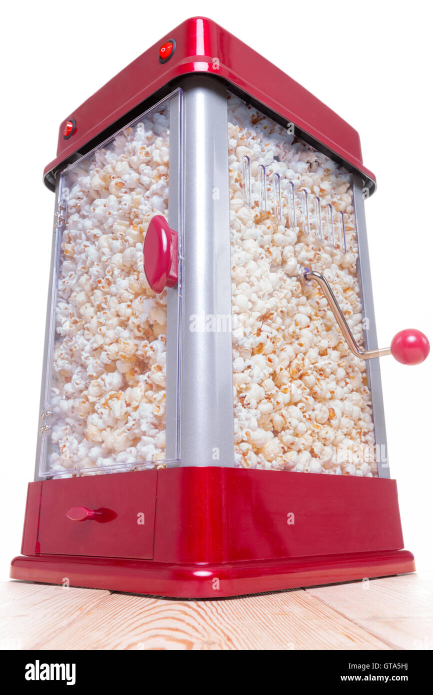 Low angle view on red and gray full popcorn maker on table with handle and white background Stock Photo