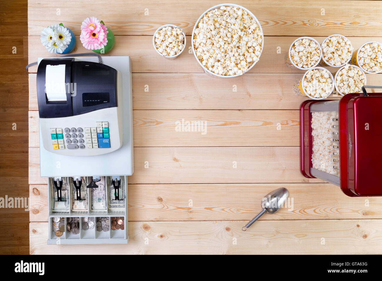Bowls of fresh popcorn alongside a till or cash register with an open drawer displaying American dollar banknotes and coins and Stock Photo