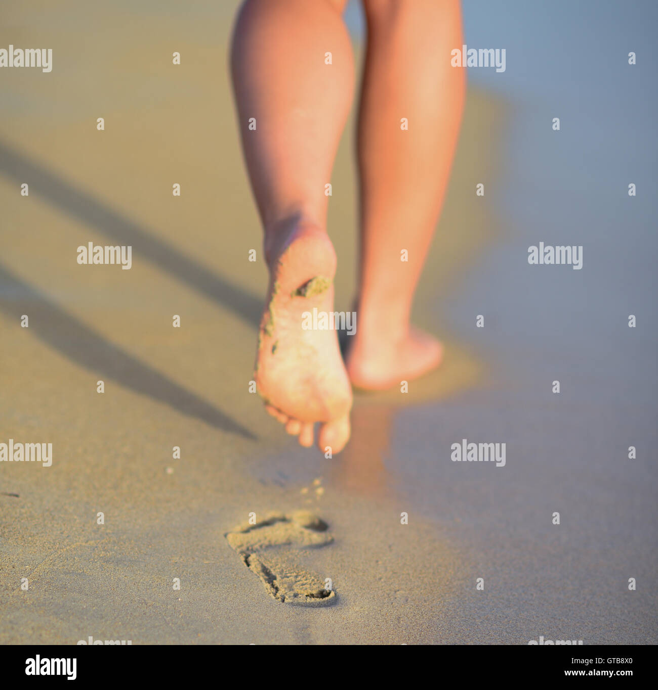 Beach travel - woman walking on sand beach leaving footprints in the ...