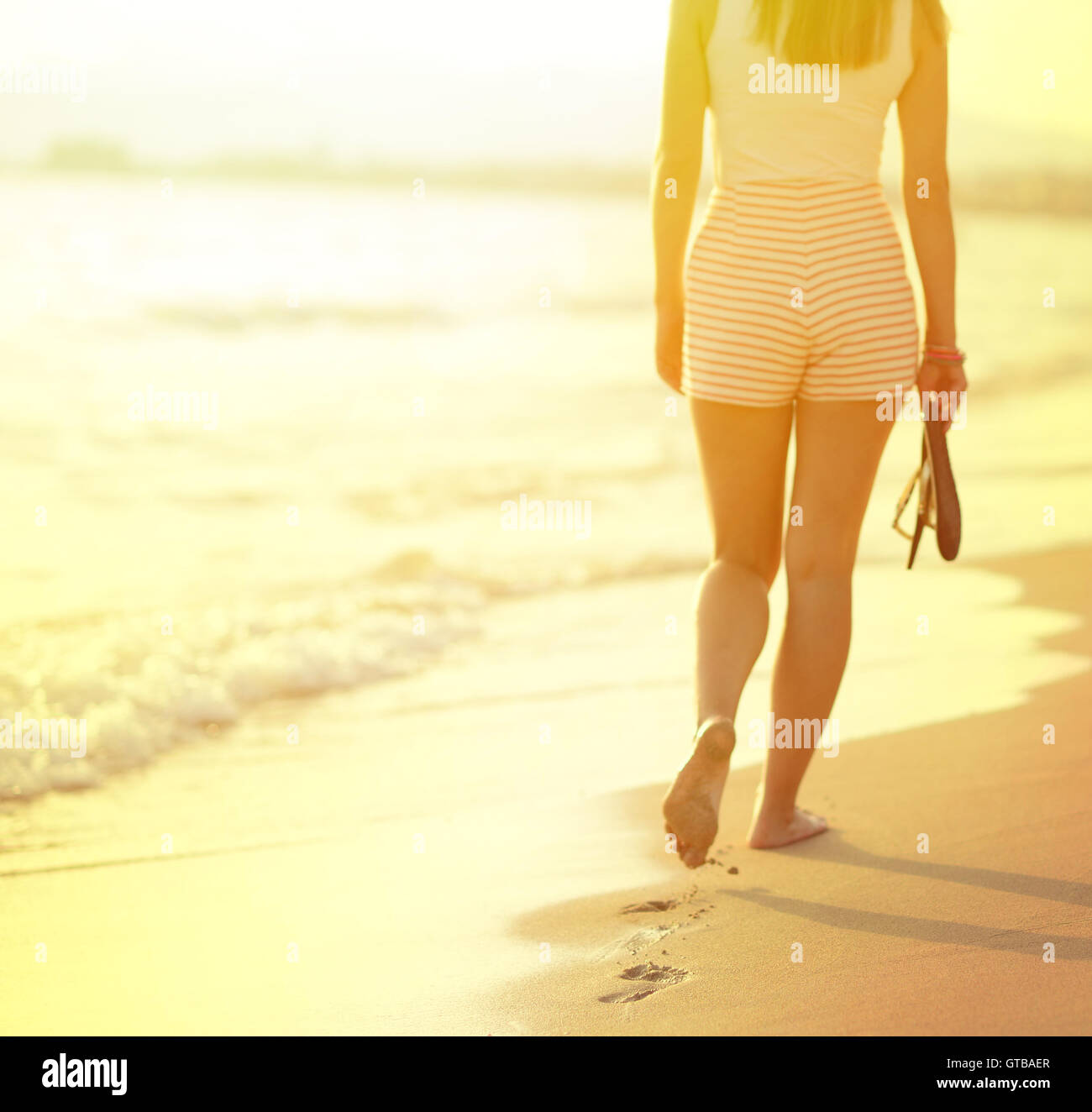 Beach travel - woman walking on sand beach leaving footprints in the ...
