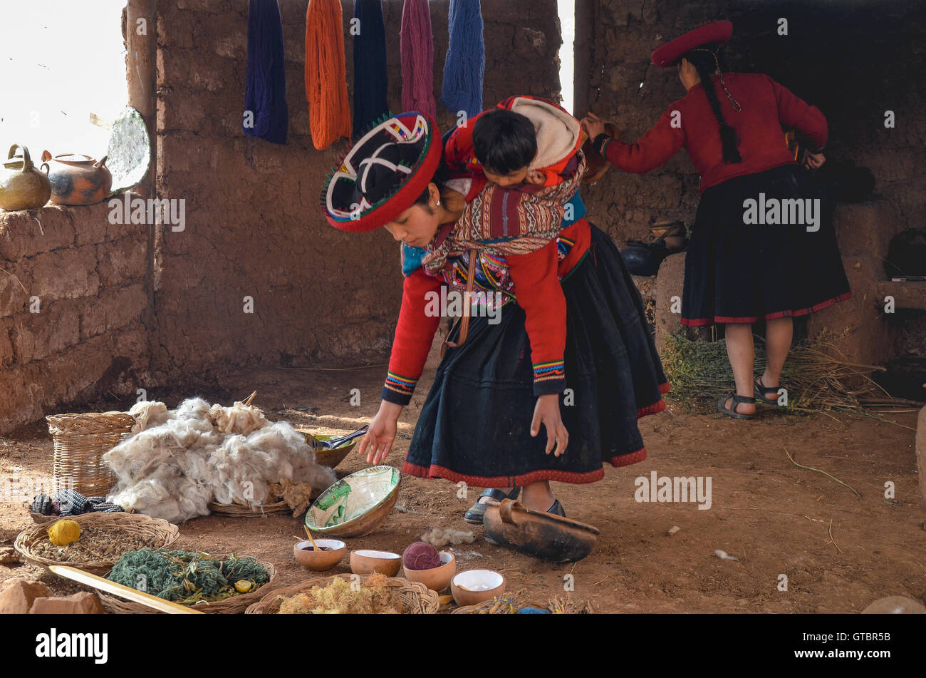 Native woman dressed in traditional colourful clothing explaining the dyeing threads and weaving Stock Photo