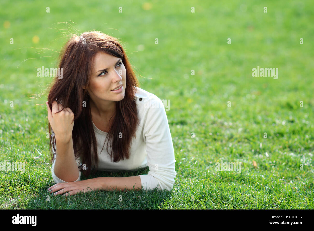 Portrait of young woman lying on a green lawn Stock Photo - Alamy