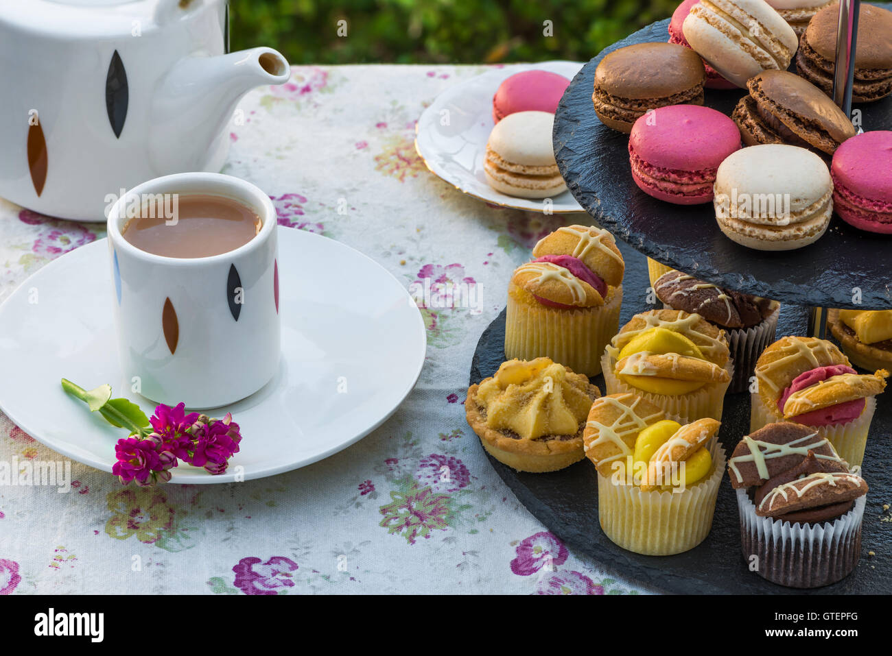 Tea with cakes and macaroons set up on the table in the garden Stock Photo