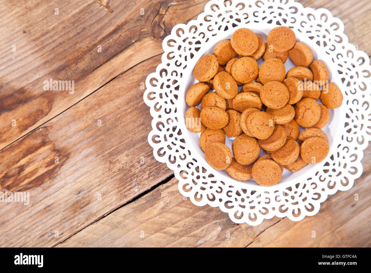 Traditional Dutch candy pepernoot on white plate on wooden background Stock Photo
