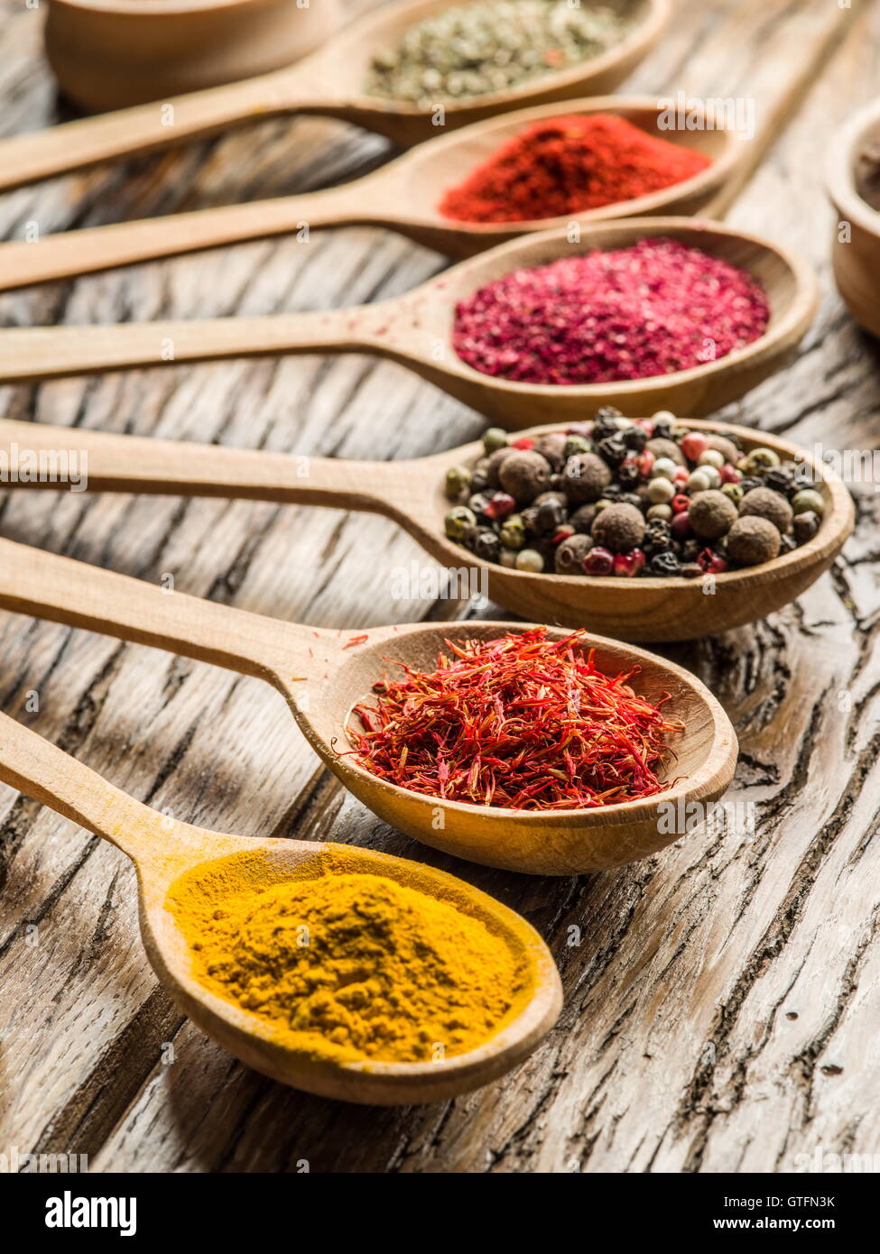 Assortment of colorful spices in the wooden spoons on the wooden table. Stock Photo