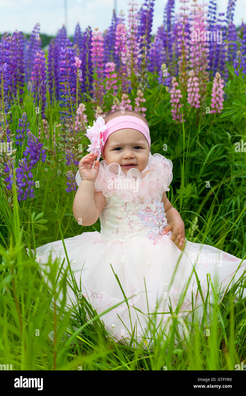 Little girl in an elegant dress sits on a grass Stock Photo - Alamy