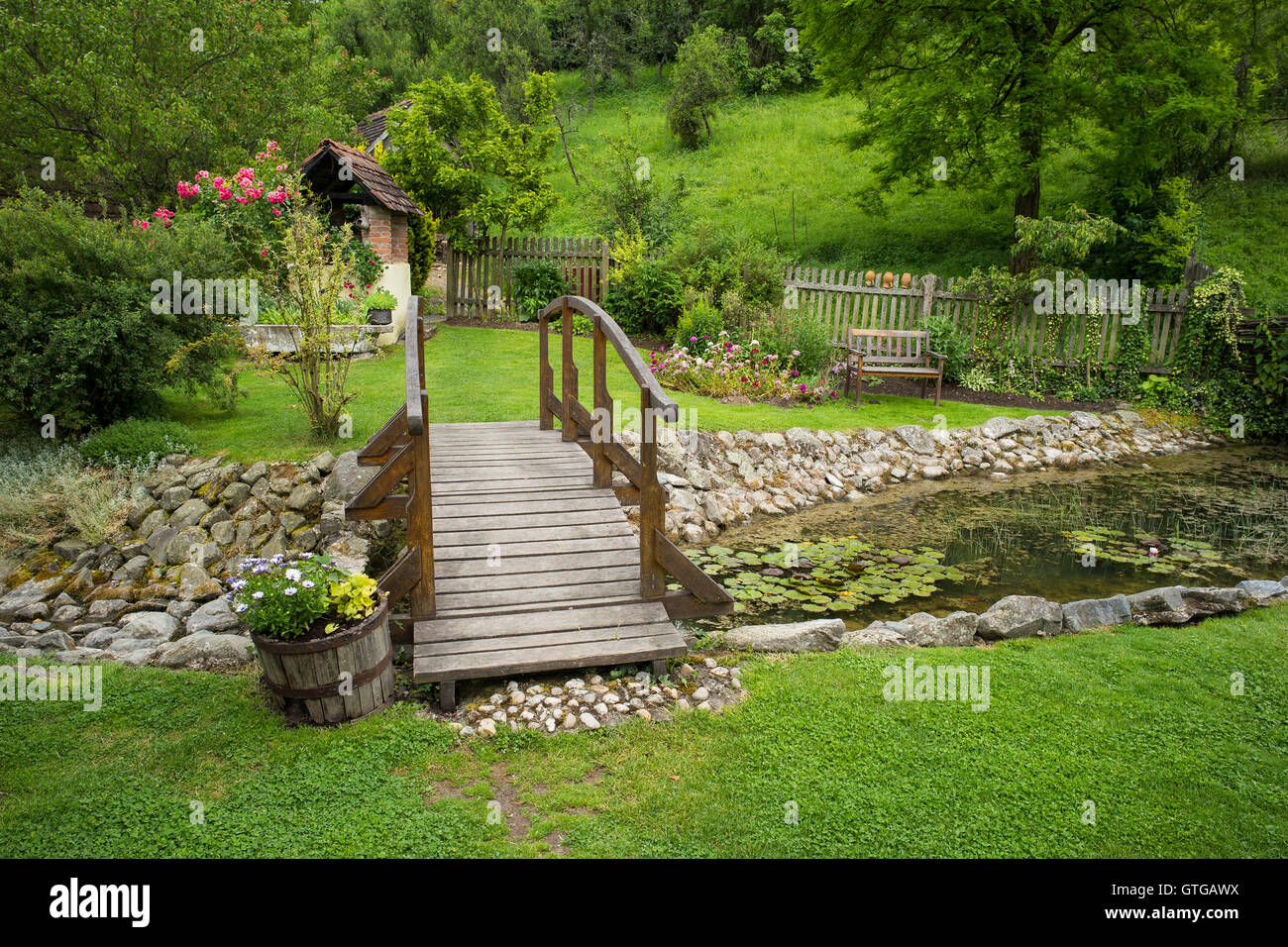 A wooden bridge over a pond in a garden in summer Stock Photo