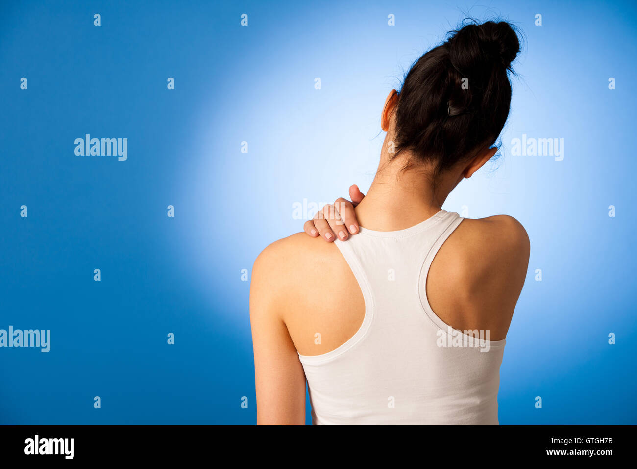 Waman having pain in her neck over blue background Stock Photo