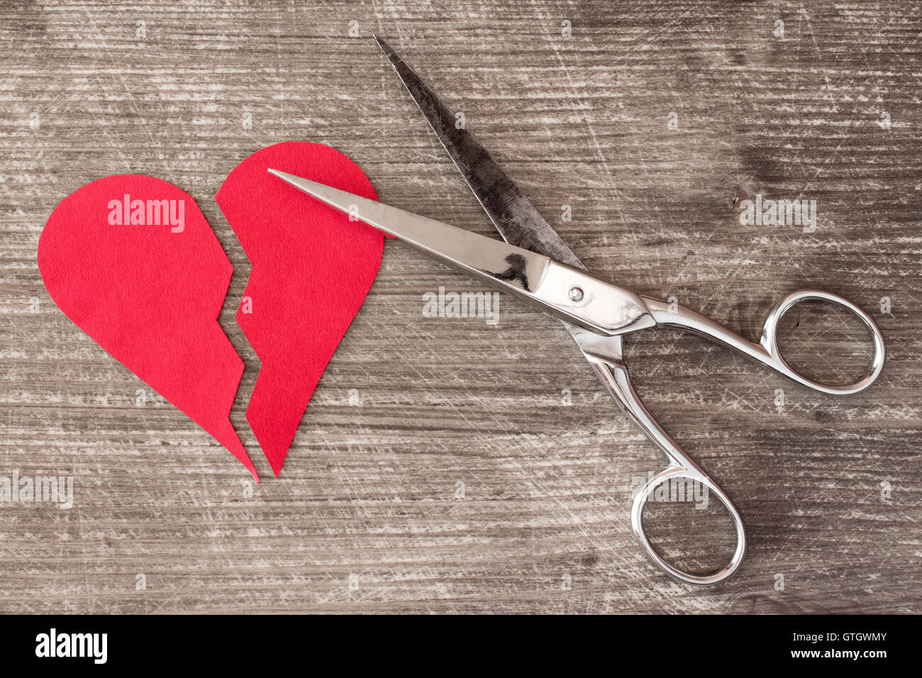 Broken red heart and scissors on a wooden background Stock Photo
