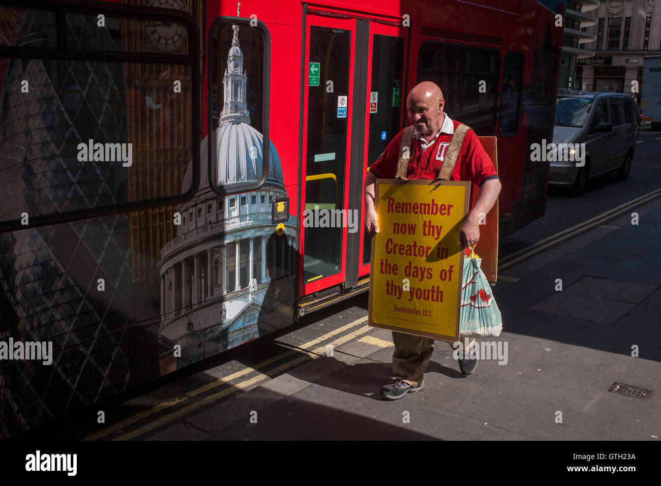 A Christian alongside a London tour bus carries a sandwich board quoting the words of Ecclesiastes 12.1 with the Biblical message that youth should remember their creator. Stock Photo