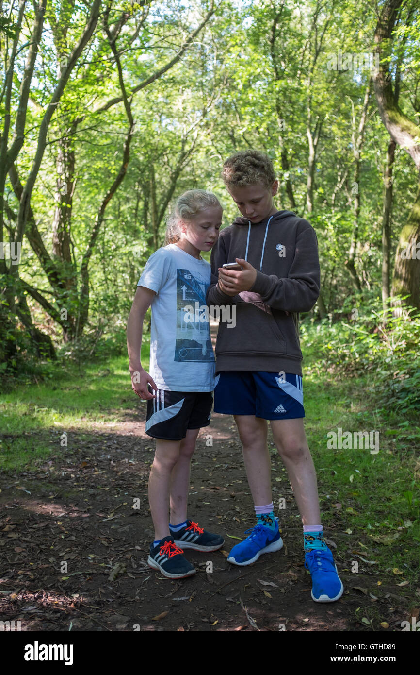 Two children playing Pokemon Go in the countryside Stock Photo
