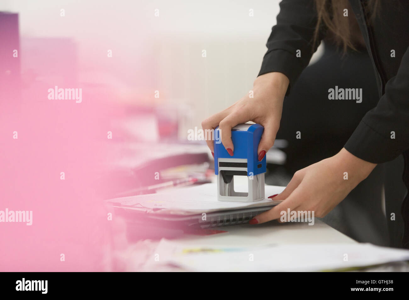 Businesswoman using stamp on paperwork in office Stock Photo