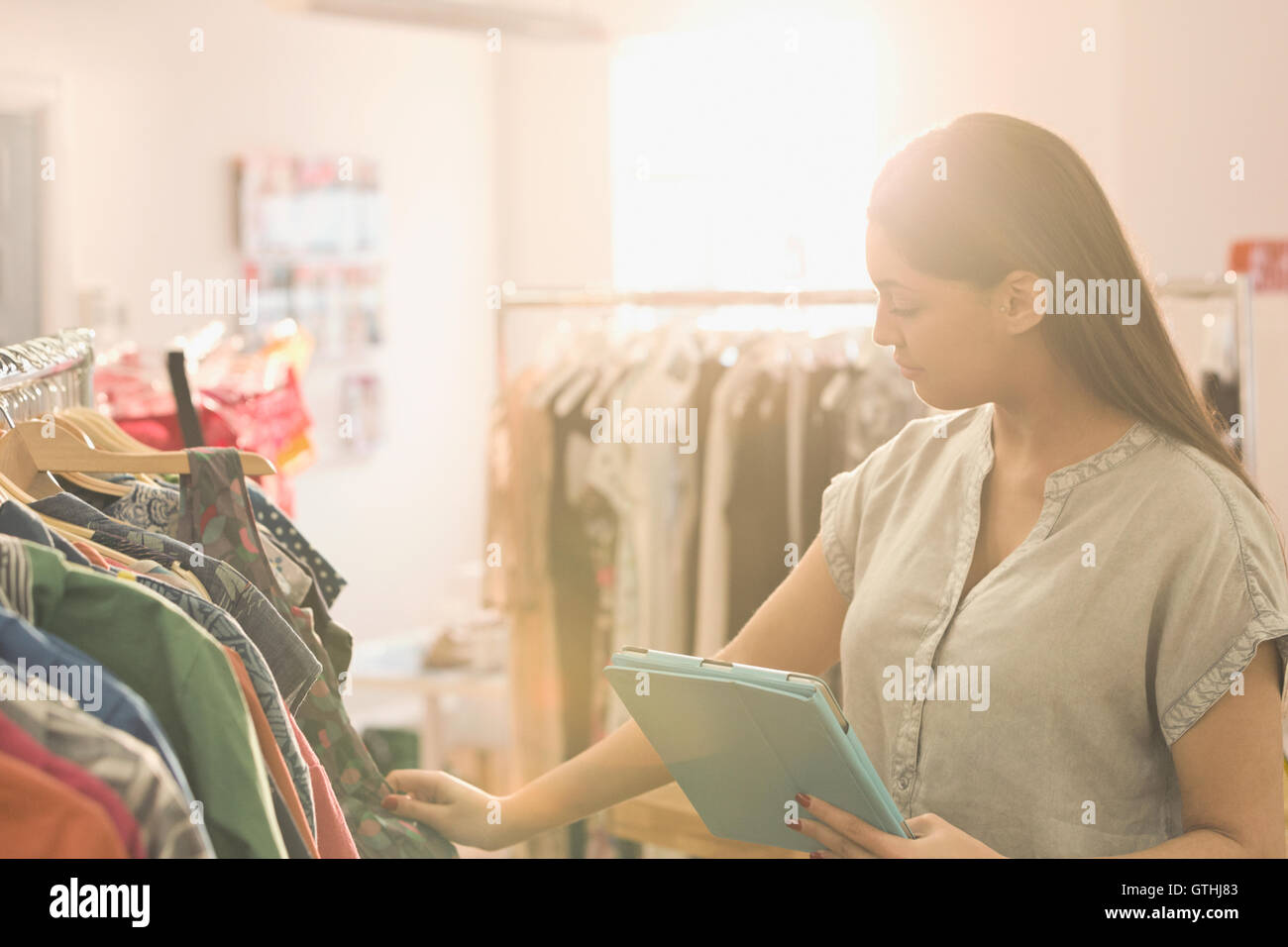 Fashion buyer with digital tablet browsing clothing on rack Stock Photo