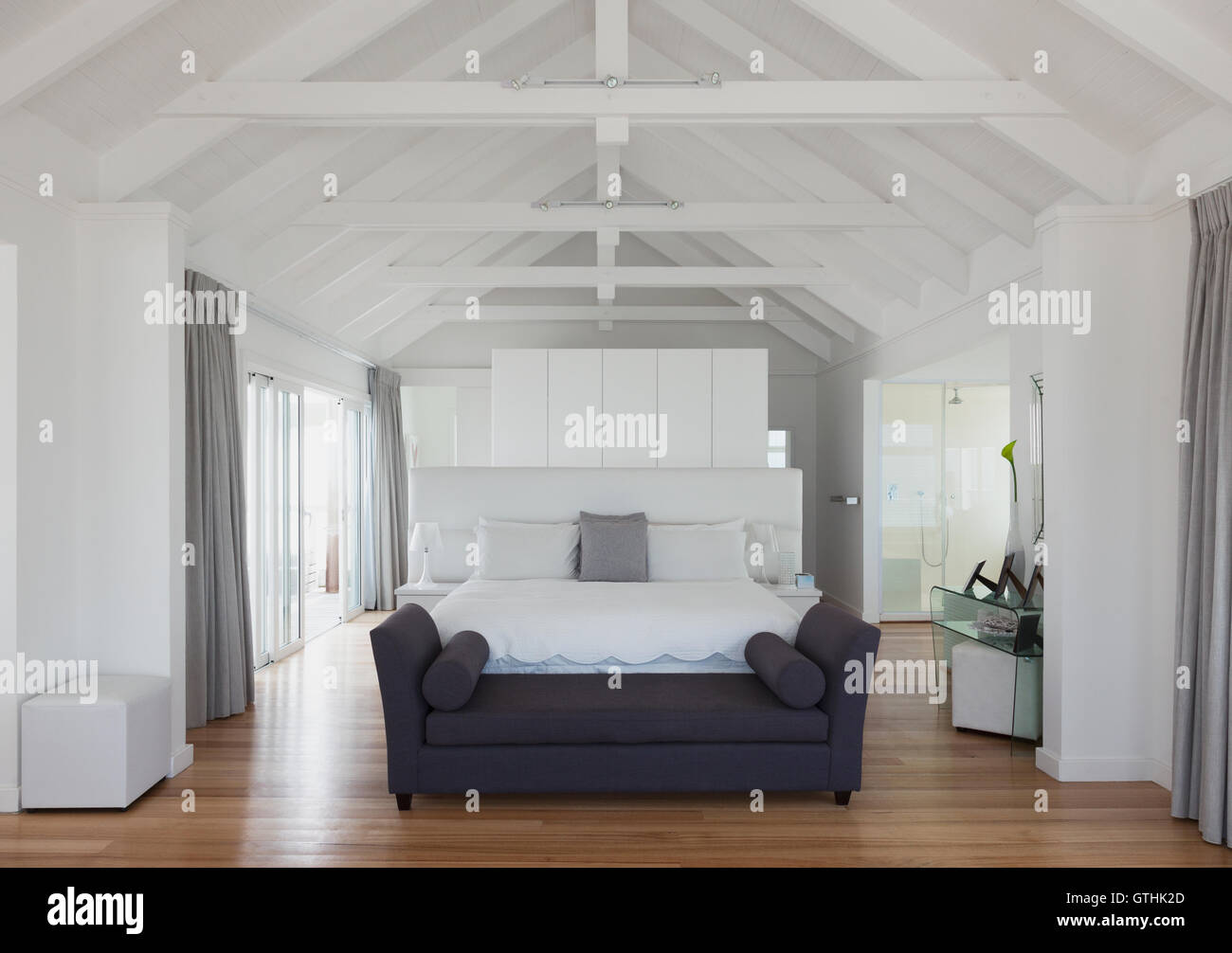 White vaulted wood beam ceiling over bed in home showcase interior Stock Photo