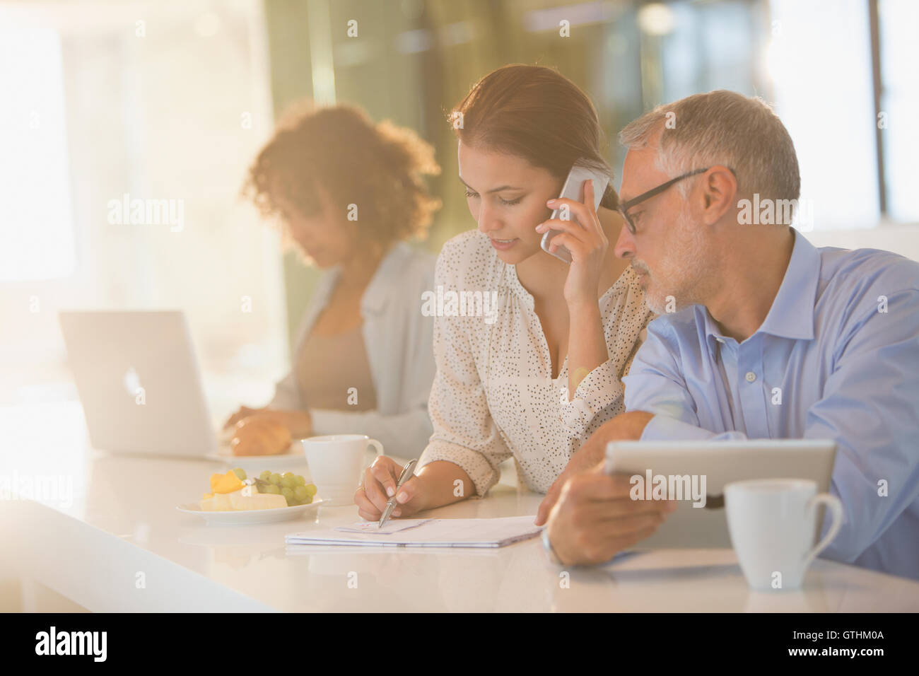 Business people drinking coffee and working at counter Stock Photo