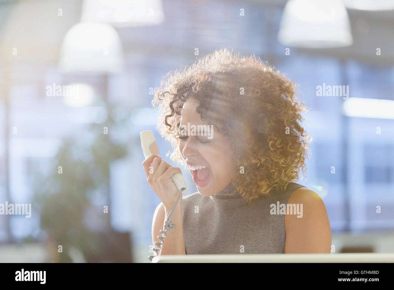 Businesswoman screaming into telephone Stock Photo