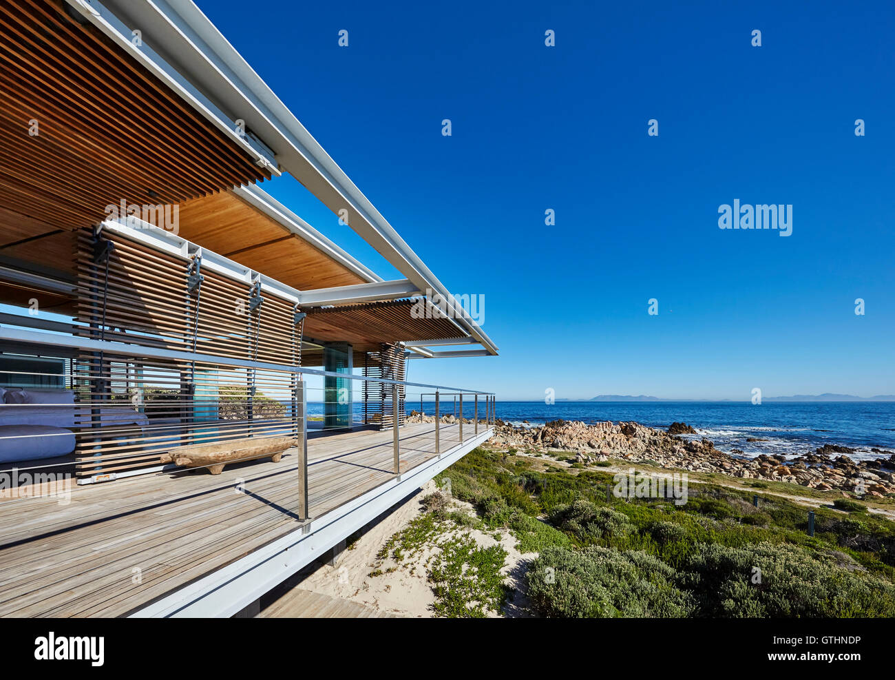 Modern luxury home showcase with ocean view under sunny blue sky Stock Photo
