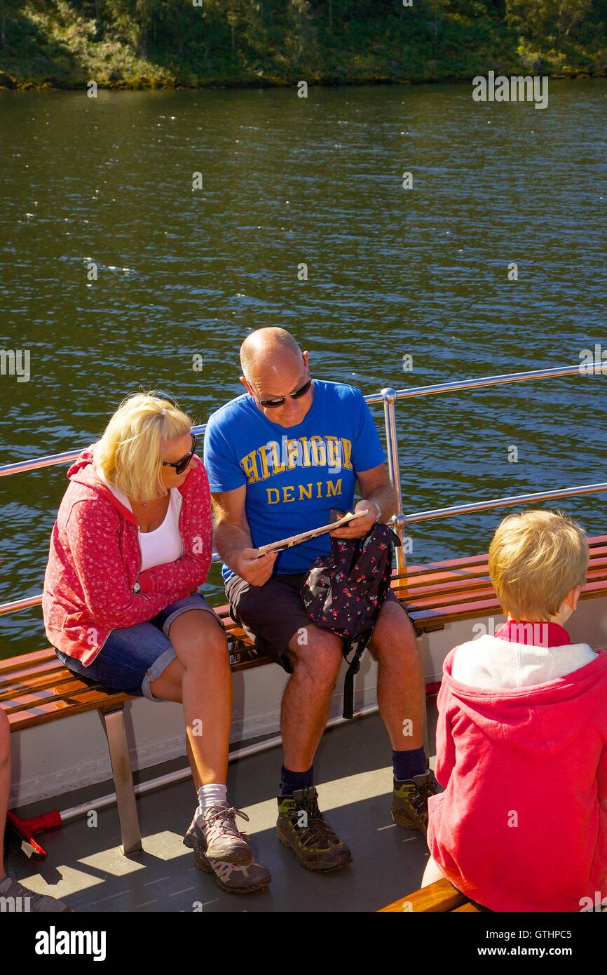 Tourists reading a brochure on a cruise aboard the bow of Ullswater Steamers. Ullswater, Penrith, The Lake District, UK. Stock Photo
