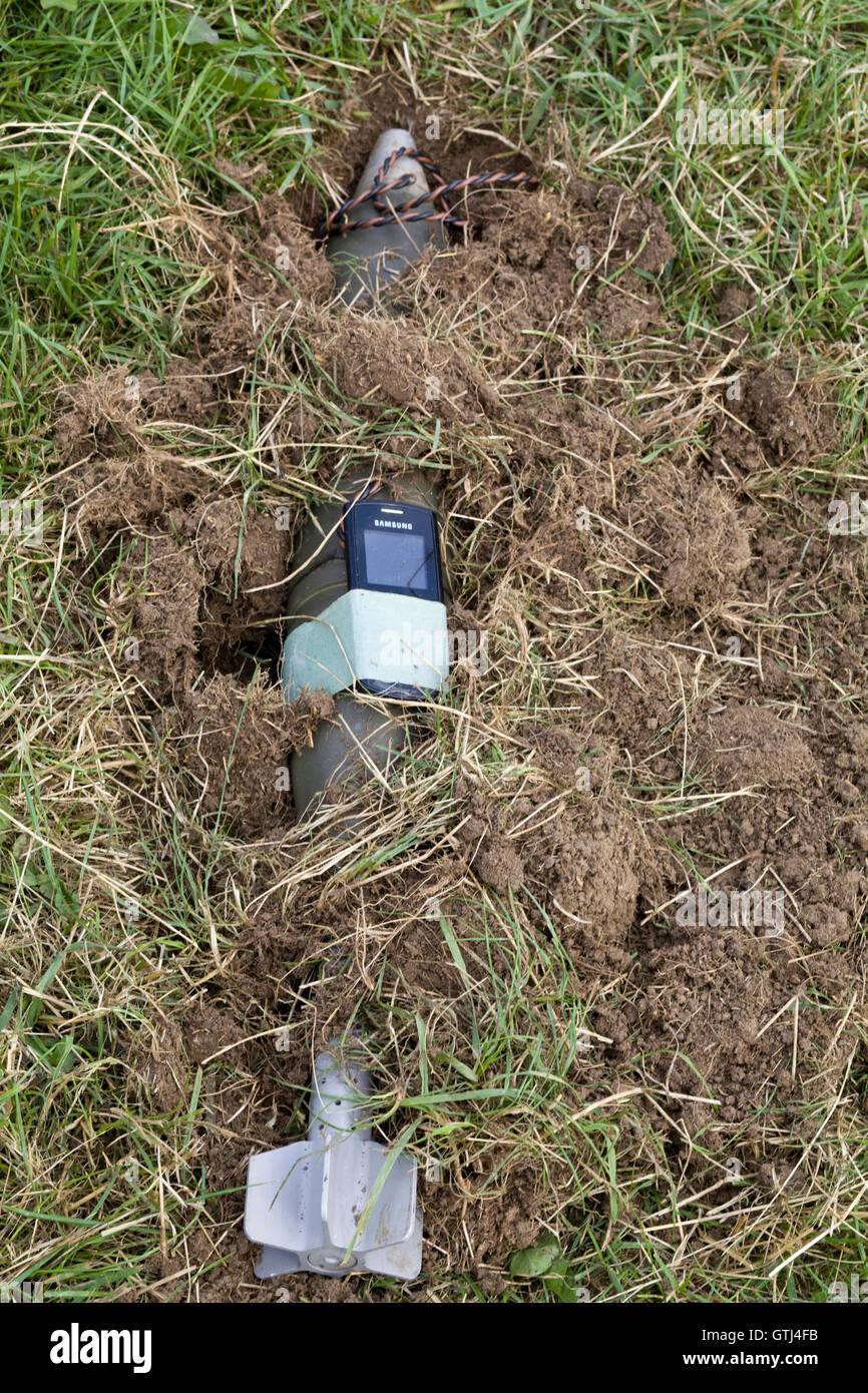 surface-to-air missile with a mobile phone attached to it uncovered in the dirt Stock Photo