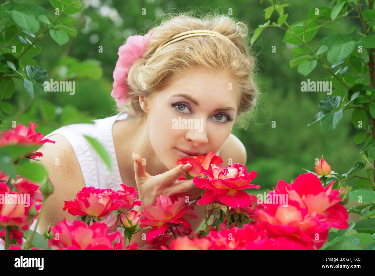 Woman in pink rose garden smelling Stock Photo - Alamy