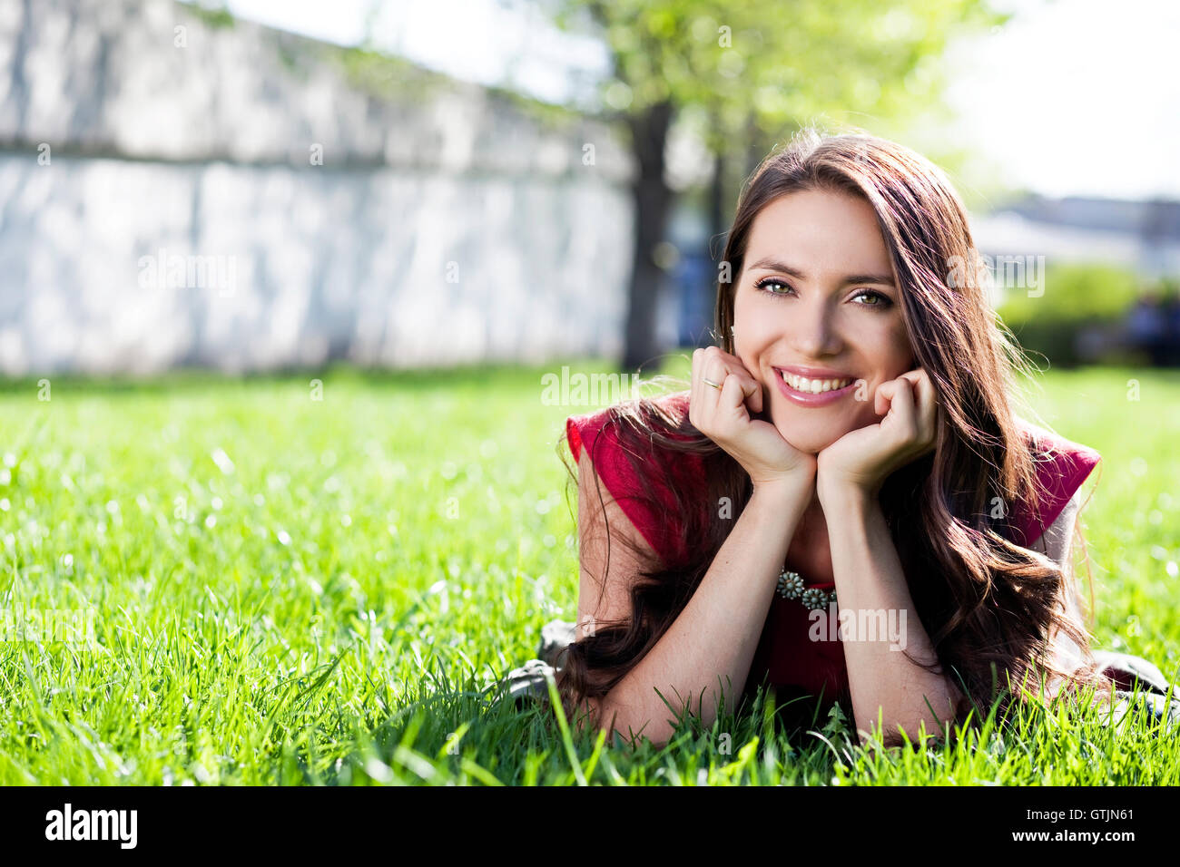 Portrait of young woman lying on a green lawn Stock Photo - Alamy