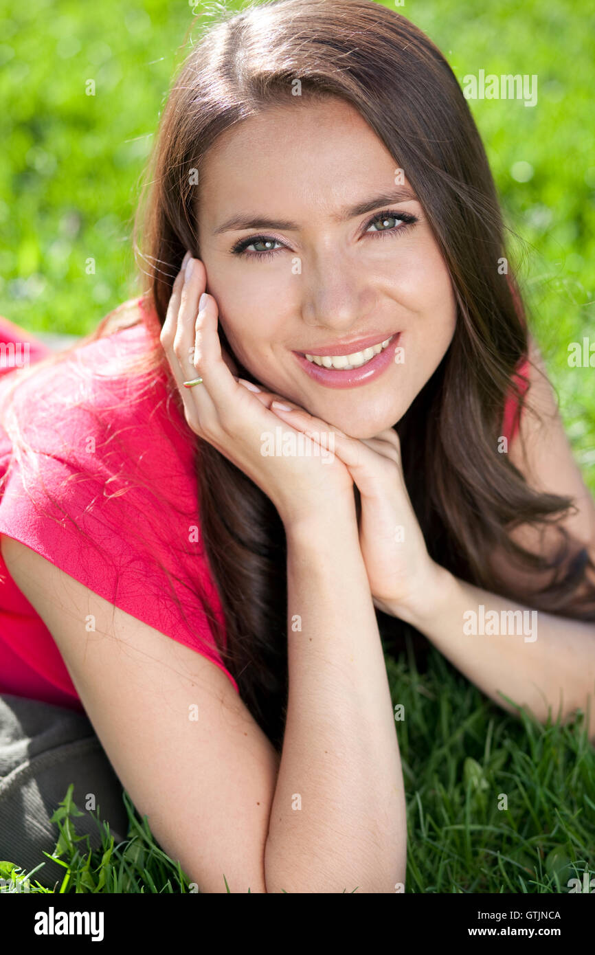 Portrait of young woman lying on a green lawn Stock Photo - Alamy
