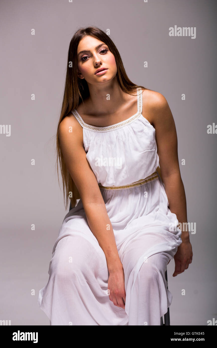 Pretty young woman with long hair in white dress in studio Stock Photo ...