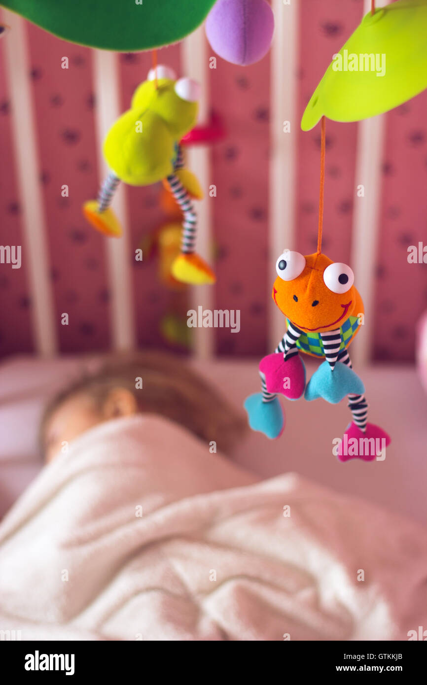 Baby bed with mobile toy above it; baby sleeping Stock Photo