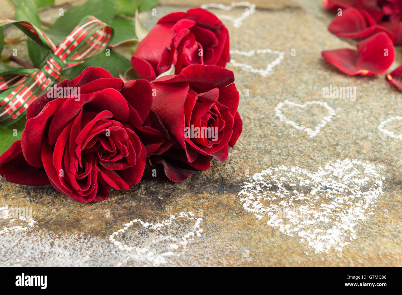 Red roses bouquet with ribbon on a stone table Stock Photo