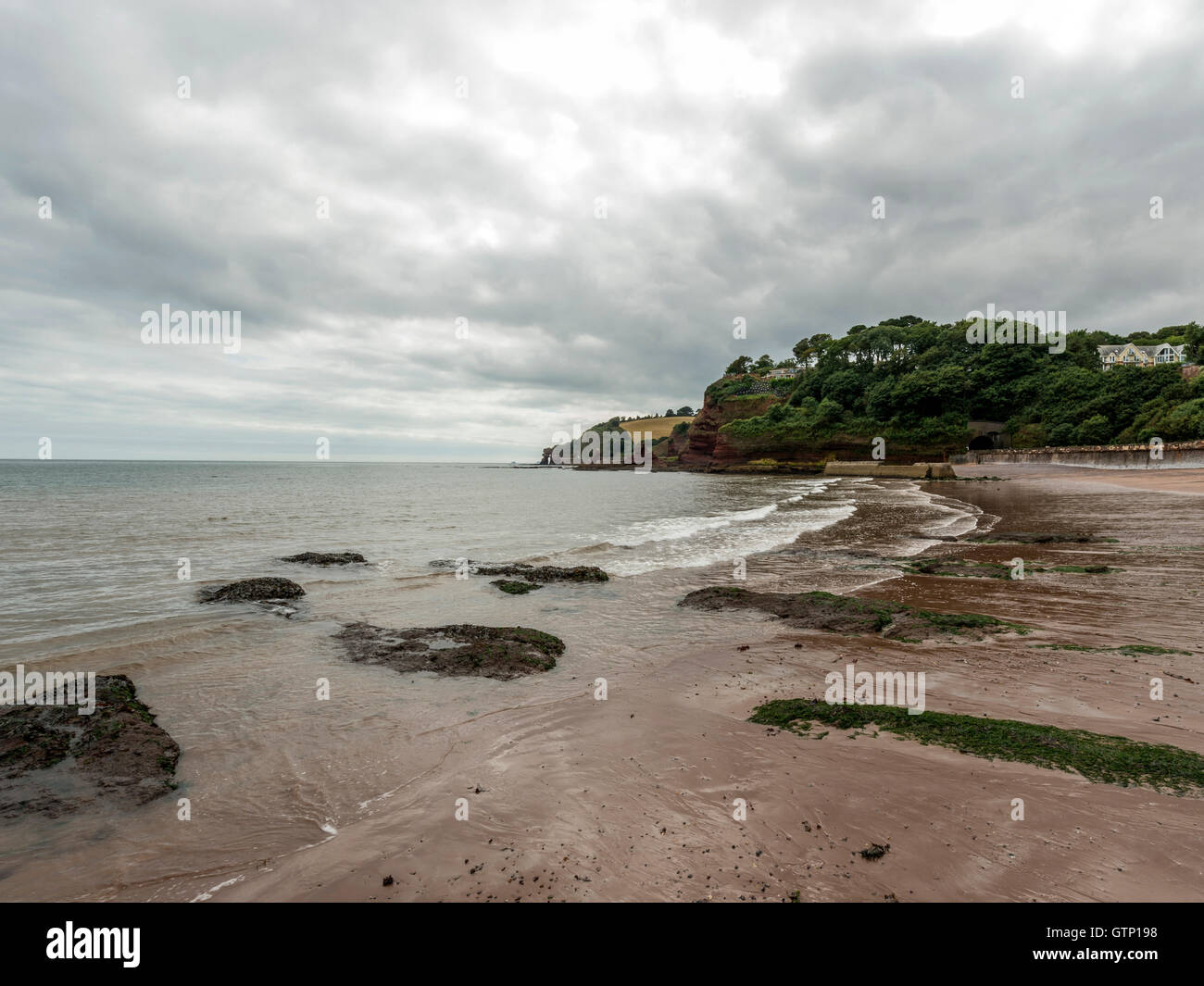 Beautiful landscape depicting storm clouds casting shadows over the South West Coastal Path / beach at Dawlish, Devon. Stock Photo