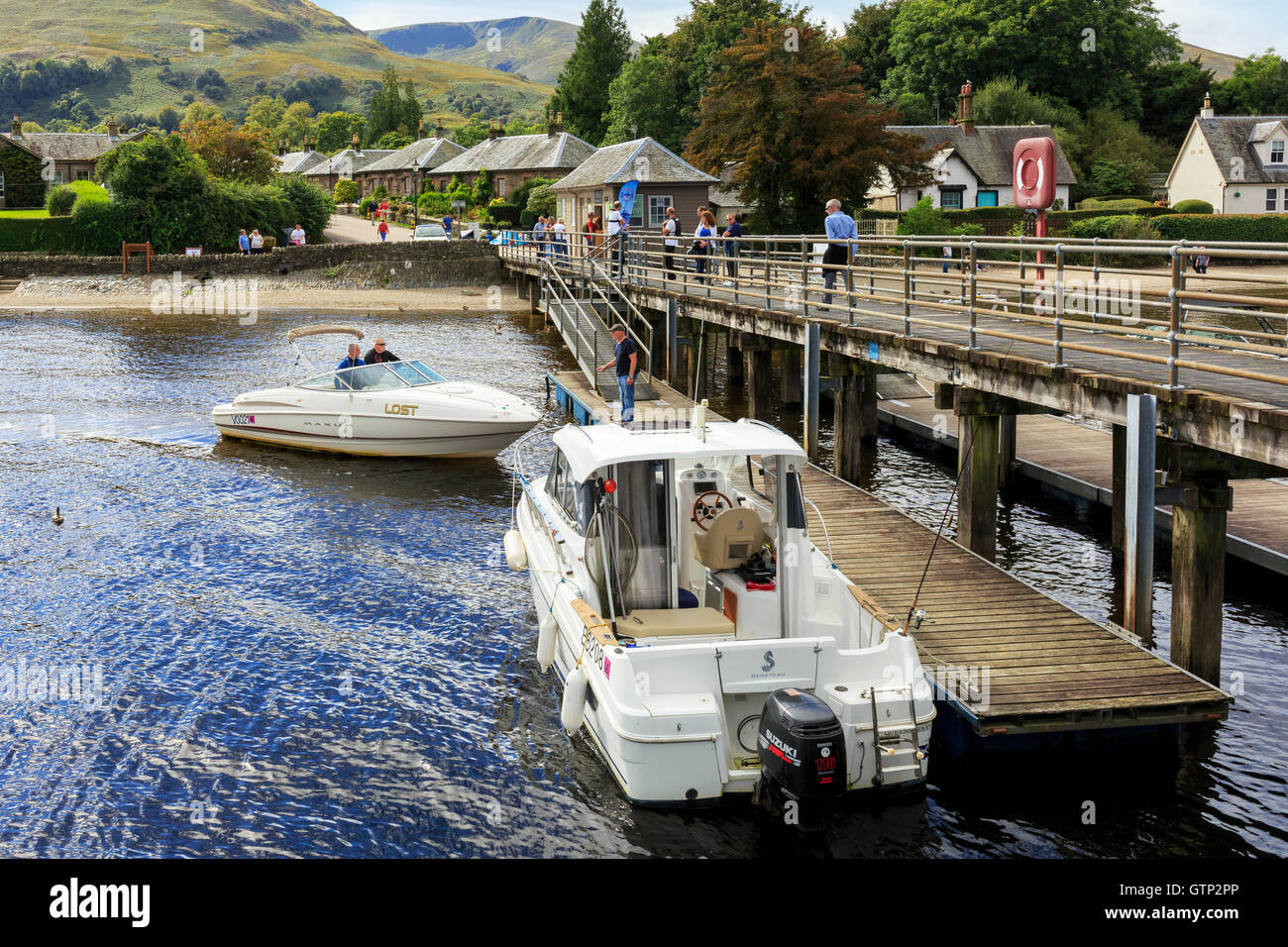 Pier at Luss, Loch Lomond, with two motor boats and tourists, Scotland