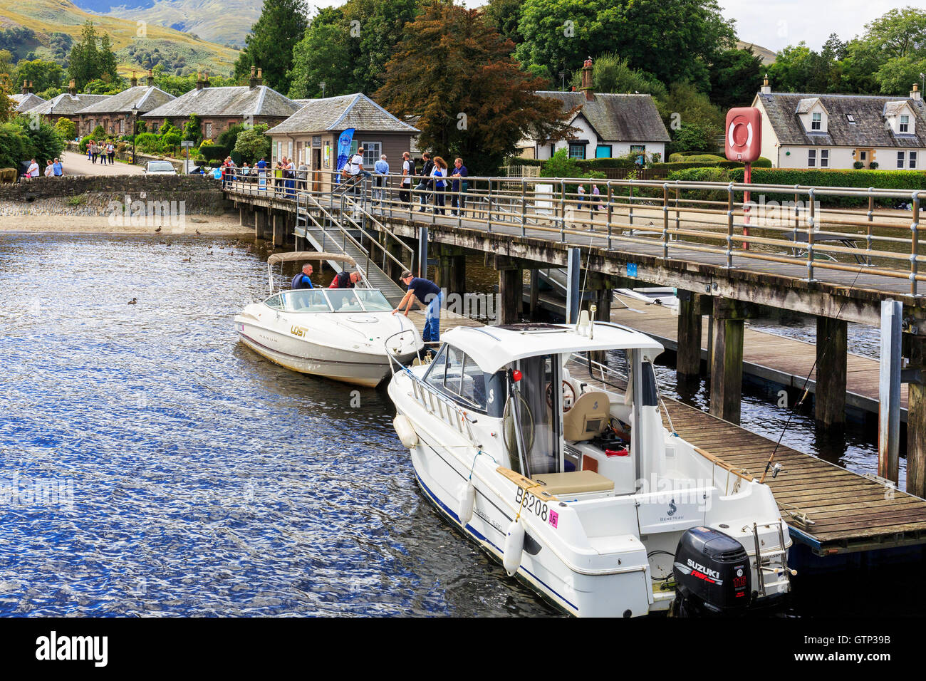 Pier at Luss, Loch Lomond, with two motor boats and tourists, Scotland